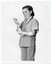 B&W photo of a girl wearing a hand and arm orthopaedic splint on each arm. She is looking down at her right hand and arm. She is wearing a short-sleeved shirt and trousers. Behind her is a plain background.