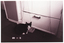 B&W photo of a cat sitting in front of a food container and small bucket, both of which have strings attached to them. Behind the container and bucket is a cupboard.  The photo is date-stamped "89 1 5" in white text on the bottom left side of the image layer. This self-made kitchen aid is described in an article on page 10 of the March, 1989 edition of Arthritis Update in an article by Occupational Therapist, Pat Dwyer. Titled 'Suggestions for independent living', it outlines the steps taken by Arthritis Foundation member, Margaret, to facilitate the daily tasks involved when living independently.