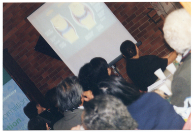 COL close up photo of seminar participants from behind, watching slides being projected onto a screen.