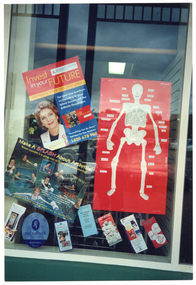 COL photo of three large posters and several information brochures adorning a shop window.