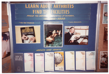 COL photo of one panel from a large freestanding display board. Under the heading, "LEARN ABOUT ARTHRITIS FIND THE FACILITIES" is the sub-heading "PHONE THE ARTHRITIS FOUNDATION OF VICTORIA (03) 862-2555". Below that are three photos under the following sub-headings: "SELF HELP PROGRAMS" (with a photo of 'The Arthritis Helpbok' below); "APPROPRIATE TREATMENT" (with a photo of two people in a hydrotherapy pool); and "LOCAL RESOURCES' (with a photo of a man making a telephone call while looking at a large Community Directory). Below the photos is the sub-heading, "LEAFLETS ABOUT ARTHRITIS", followed by a row of sample leaflets attached to the board. The leaflet titles are as follows: "HOW TO LIVE WITH ARTHRITIS", "About Arthritis", "About Osteoarthritis", "About Rheumatoid Arthritis", "About Recreation and Leisure", "About Diet", "About Gout", and "About Arthritis in Children".
