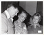 B&W close-up photo of three people standing close together and looking down. The brickwork of the interior walls of the building is visible in the background.