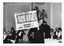 B&W photo of a man holding up an advertising billboard.  The text on the billboard is, "THE WORLD FAMOUS SEEKERS BALLROOM ARCADIA CORK SUNDAY NOVEMBER 21 9-2 7/8". There is some additonal text in smaller font which is illegible. Placed around various points on the billboard are the song titles "I'll Never Find Another You", "In A World Of Our Own", and "The Carnival Is Over". In the background, there are groups of people seated at round tables.