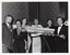 B&W photo of a small group of people gathered around a large model of a Malaysian Airlines aeroplane on a stand.