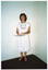 COL photo of a woman standing in the corner of a room, holding some money (notes) and leaflets.