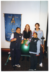 COL photo of four people posing for a photo around some gym equipment. Behind them, there is a blue and gold banner on or against the wall. The banner contains the text "ARTHRITIS VICTORIA", "OSTEOPOROSIS VICTORIA", and "MUSCULOSKELETAL HEALTH", with two corresponding logos.