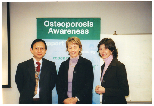 COL photo of three people posing for a photo in front of a large freestanding vertical banner. The banner contains the text heading, "Osteoporosis Awareness", followed by words such as "support", "advocacy", and "research".