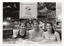B&W photo of a man and two women sitting in a hot tub/spa. Two of them are holding up PhysiCal branded take-away drink cups. Behind them, there is a display board with a sign and some photos of people in warm water (such as a hot tub/spa or a swimming pool). The sign is titled, "Move it or lose it", followed by a logo and the text "ARTHRITIS FOUNDATION OF VICTORIA Yarra Boulevard, Kew, 3101 For Further Information: Tel. (03) 862.2555". On either side of the sign, there is a photo of a woman in a not tub/spa. A third photo (directly below the sign) depicts the same woman in a spa with two children (one child is obscured). A fourth photo (right) depicts a small group of people partaking in warm water exercises in a swimming pool. There are two small photos superimposed onto the larger photos (each depicting a close up of a man's face) with the text, "Bananas are good enough for me".