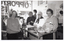 B&W photo of four women inside a shop. One woman is standing in front of the counter (a glass display cabinet), while the other three women are standing behind it. They are all looking directly at the camera and smiling. On top of the glass counter, there are some brochures on a stand, a sales book, some printed booklets stacked loosely, and some fresh fruit in a cane basket. One of the brochures is titled, "FIGHTING ARTHRITIS". Behind the women, is the front shop window, with the painted text, "OPPORTUNITY SHOP" (partially obscured), appearing in reverse. On the wall behind them, there is a small sign resting against the wall above the meter box. The text (partially obscured) reads, "...WHICH IS... VOLUNTEERS... IS USED FOR RESEARCH BY THE ABOVE ASSOCIATION."