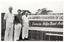 B&W photo of three men standing next to a large horizontal banner affixed to an exterior wall constructed from decorative concrete blocks (also known as "breeze blocks"). At the top of the banner, in large font, is the text (partially obscurred), "ARTHRITIS FOUNDATION OF VICTORIA", preceeded by a telephone number. Across the centre, there is the text, "Exercise Helps Beat Arthritis" (partially obscured). Across the bottom of the banner, there is the text (partially obscured), "...ER PROJECT FUNDED BY VICTORIAN HEALTH PROMOTION FOUNDATION”.