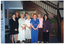 COL photo of a group of people posing for a photo inside a building. Behind them are a wall display of brochures, some directional signs indicating the location of the building's commercial tenants, and a wooden staircase leading to the next floor.