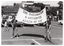 B&W photo of two boys each holding up a wooden pole onto which a large banner is attached. They are in a carpark, with some houses, trees, and multistorey buildings evident in the background. Both boys are wearing a t-shirt with the text, "I FIGHT ARTHRITIS", and shorts. The text on the banner says, "THE RHEUMATISM & ARTHRITIS ASSCN OF VIC". There are several cars parked in the car park, including two vintage cars to the right of the frame. A few people are looking at the vintage cars.