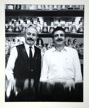 2 men smiling at a bar. 
