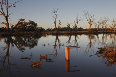 Landscape photo of a lake with a sunken chair and table. 