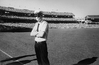 A black and white photo of a police office on a football field. 