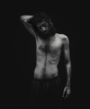 A black and white photo of a man with no shirt. 