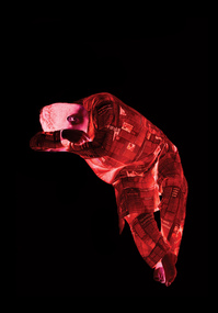 Monochromatic figure of man with head in his arms, lit up with red light against black background.