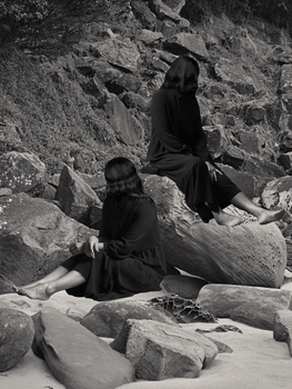 Black and white photomontage of two women sitting on rock.