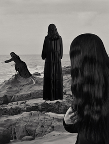 Black and white photograph of three women on the shore of a beach