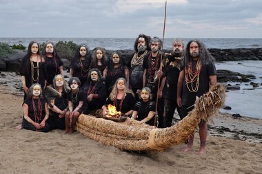The extended family of First Nations artist Maree Clarke is gathered on the beach with a traditional river reed canoe.