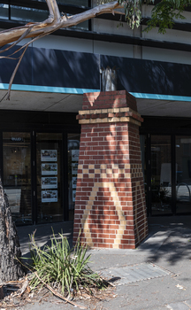 A brick sculpture of a chimney in a suburban street