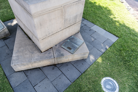 A detail of a stone statue. If features a bronze book open to a page.