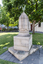 A large sculpture of a stone cut birdcage - there is a sheet covering the birdcage with a with a bronze bird lifting it off. 