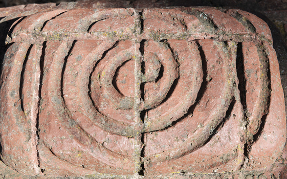 A detail of a swirling pattern on a brick sculpture.