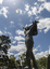 A statue of a naked man waving a piece of cloth throwing his hands up in the air. The whole statue including the cloth is cast in bronze.