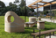 A large abstracted sculpture made out of stone that resembles a play structure structure or outdoor seating. it is in a grassy part out the front of a community hub. 