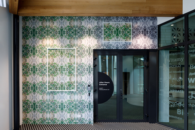 A geometric pattern print covering a wall with a vinyl wrap. There are 2 framed photos with the same pattern hung on the wall.  