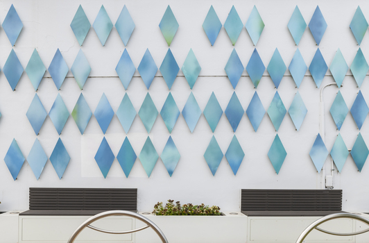 The exterior of a small library building covered in approximately 100 blue metal diamond shaped motifs. 