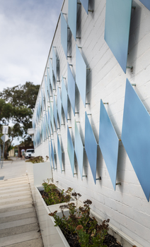 The exterior of a small library building covered in approximately 100 blue metal diamond shaped motifs. 