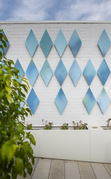 The exterior of a small library building covered in approximately 100 blue metal diamond shaped motifs. 