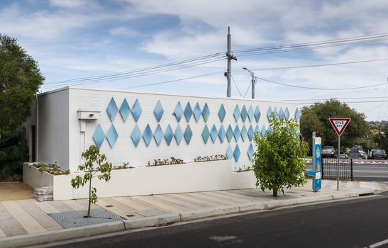 The exterior of a small library building covered in approximately 100 blue metal diamond shaped motifs. 