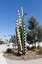 A large sculpture consisting of a series of striped and unstriped metal poles sticking out of the ground in a single cluster in a haphazard manner. there are approximately 15 of them and the sculpture is located on a street corner.