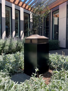 A small bronze house sculpture in a courtyard. 