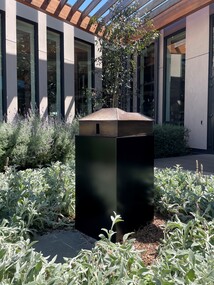 A small bronze house sculpture in a courtyard. 