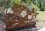 A large rusted cut out sculpture with native floral emblems form the local area. it is located in a bush setting along a creek.