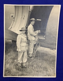 Black and white photograph on card of Matron A Sage and Commanding Officer Colonel Leah, smiling and packing a plane in New Guinea in January 1944. 