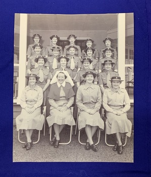 A black and white photograph of 18 women wearing their uniforms and sitting in four tiered rows, 17 nurses and 1 matron.