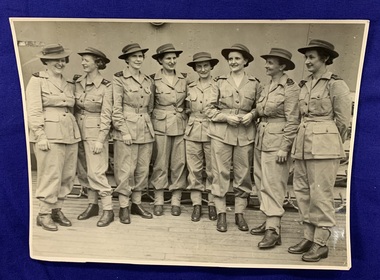 A black and white photograph of 8 women in uniform standing in a row, talking smiling and laughing with each other. The first Australian Army Nurses to arrive in New Britain, from left to right Sisters Jean Gracey, Marjorie Smith, Kathleen Barnes, Gertrude Muller, Mary Wilson, Marie O'Laughlan, Dorothea Harrison and Gwen Dwyer. 