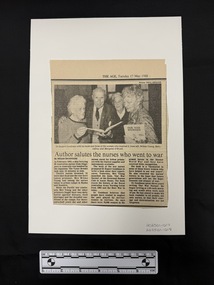 Newspaper clipping with publication title and date at the top and a photograph above three columns of text. Black and white photograph is of three older women and one older man holding copies of a book in their hands.