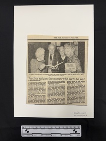 Newspaper clipping with publication title and date at the top and a photograph above three columns of text. Black and white photograph is of three older women and one older man holding copies of a book in their hands.