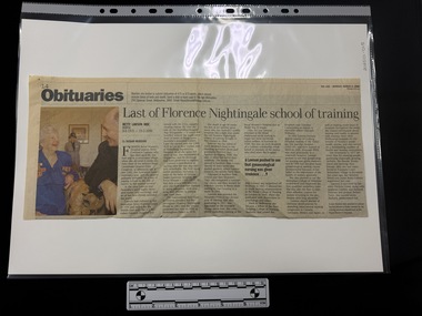 Newspaper clipping with a colour photograph on the left hand side of an older man and woman in the foreground and an older woman in the background.  The obituary has six columns of text.