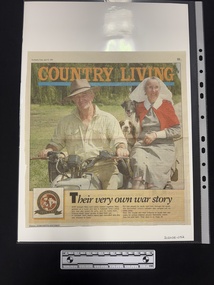 Page mostly taken up with large colour photograph of an older man in a hat, an older woman in an army nurses uniform with two dogs sitting on a motocycle.  Underneath photo is two column of text