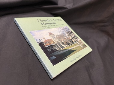 Green book with title, author information and a photo of a building scene on the front cover