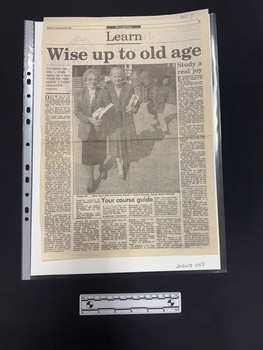 Full page, three articles using six columns of text surrounding a large black and white photograph of two older women holding books, standing outside