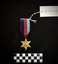 Medal from yellow copper zinc alloy with somewhat sharp six points. The obverse has a central and textured design of the Royal Cypher 'GRJ VI', surmounted by a crown. A circlet, the top of which is covered by the crown, surrounds the cypher and is inscribed 'THE PACIFIC STAR'. The ribbon is tactile with red, navy, and light blue stripes. [I believe that the ribbon on 202508.259 and 202508.260 have been swapped at some point.]