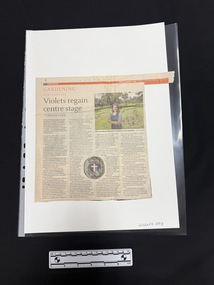 Newspaper clipping with article, four columns of text, a colour photo of a woman with a park in the background on the right and a colour photo of a [badge] in the centre.